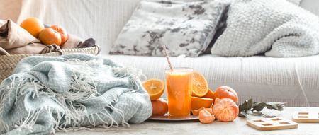Freshly-grown organic fresh orange juice in the interior of the house, with a turquoise blanket and a basket of fruit. Healthy food. Vitamin Cの写真素材