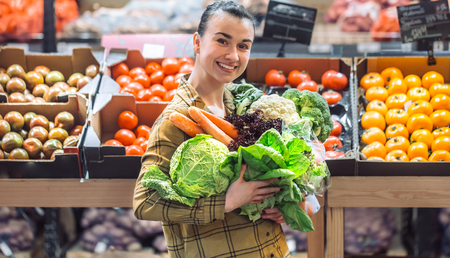 Woman in the supermarket. Beautiful young woman shopping in a supermarket and buying fresh organic vegetables. The concept of healthy eating. Harvestの写真素材