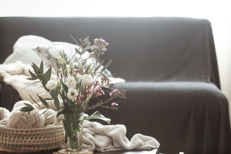Cozy home interior living room with a black sofa and a vase with flowers and decor items on a small tableの写真素材