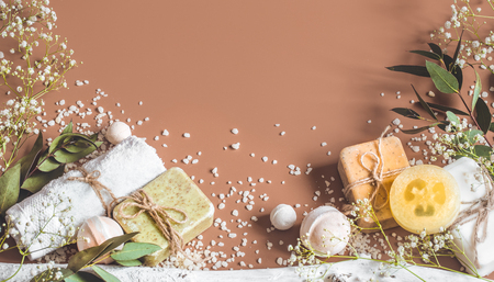 Spa concept with towels, soap, salt, leaves, flowers, bath bombs and body and face accessories on colored background. Place for textの写真素材
