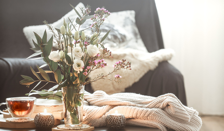 Cozy home interior with elements of decor in the living room with a black sofa and a vase of flowers and lighted candles on a small table.の写真素材