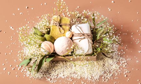 Top view of spa and body care accessories in wooden box on colored background. With soap, leaves, flowers, bath bombs and body and face accessoriesの写真素材