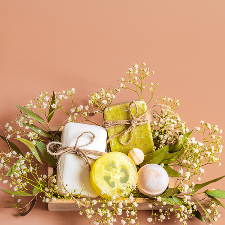 Top view of spa and body care accessories in wooden box on colored background. With soap, leaves, flowers, bath bombs and body and face accessoriesの写真素材