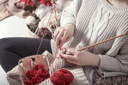 wooden spokes and red yarn in the hands of a woman on a cozy sofa . Still life photo. The concept of comfortの写真素材
