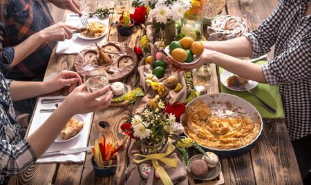 Home Holiday friends or family at the festive Easter table with Easter colored eggs. The concept of the celebrationの写真素材
