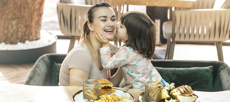 Loving family. Mom with cute daughter eating fast food in a cafe, family and nutrition conceptの写真素材