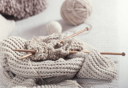 Vintage wooden knitting needles and yarn on the cosy sofa with a sweater ,with a soft focus . Still life photo. The concept of comfortの写真素材