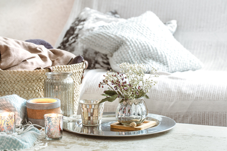 Home decorations in the interior. On the wooden background lies a turquoise blanket and wicker basket with a vase of flowers and candles. Concept of comfortの写真素材