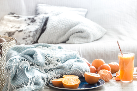 Freshly-grown organic fresh orange juice in the interior of the house, with a turquoise blanket and a basket of fruit. Healthy food. Vitamin Cの写真素材