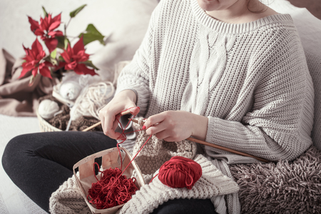 wooden spokes and red yarn in the hands of a woman on a cozy sofa . Still life photo. The concept of comfortの写真素材