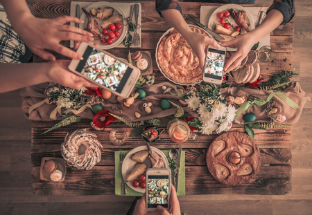 Group of friend take a picture with mobile phone before have lunch. top view. Festive table. Traditional Easter celebration, Easter holiday party.の写真素材