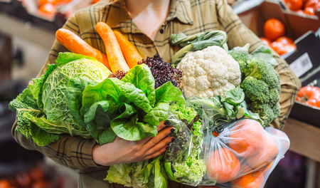Woman in the supermarket. Organic vegetables close up. Beautiful young woman shopping in a supermarket and buying fresh organic vegetables. The concept of healthy eating. Harvestの写真素材