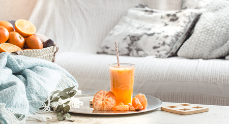 Freshly-grown organic fresh orange juice in the interior of the house, with a turquoise blanket and a basket of fruit. Healthy food. Vitamin Cの写真素材