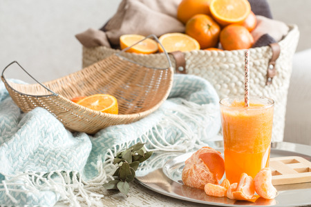 Freshly-grown organic fresh orange juice in the interior of the house, with a turquoise blanket and a basket of fruit. Healthy food. Vitamin Cの写真素材