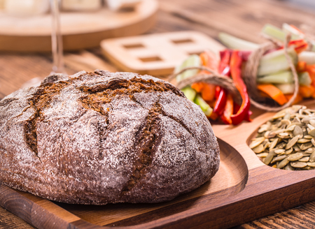 A fresh round of dark bread on a wooden plate , the concept of healthy foodの写真素材
