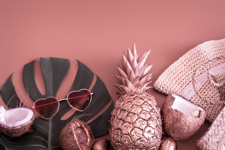 Summer tropical background with gold-colored pineapple and summer accessories with heart-shaped glasses, on a pastel colored background, the concept of creativity and styleの写真素材