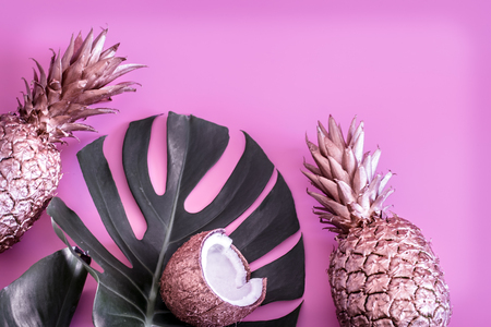 Summer tropical background with gold-colored pineapples and coconuts, on a colored pink background, the concept of creativity and styleの写真素材