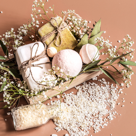 Top view of spa and body care accessories in wooden box on colored background. With soap, leaves, flowers, bath bombs and body and face accessoriesの写真素材
