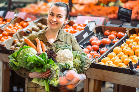 Woman in the supermarket. Beautiful young woman shopping in a supermarket and buying fresh organic vegetables. The concept of healthy eating. Harvestの写真素材