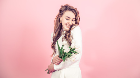 Young girl with white tulips in their hands on a colored background, the concept of women's day and holiday