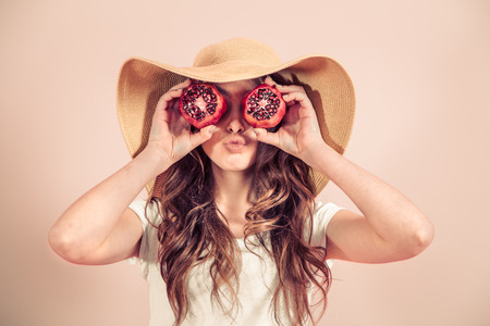 Portrait of a girl in a summer hat with fruit in her hands, concept of style and summer daysの写真素材