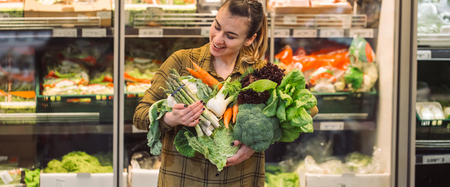 Woman in the supermarket. Beautiful young woman shopping in a supermarket and buying fresh organic vegetables. The concept of healthy eating. Harvestの写真素材