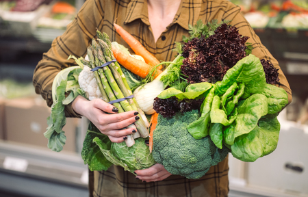 Woman in the supermarket. Organic vegetables close up. Beautiful young woman shopping in a supermarket and buying fresh organic vegetables. The concept of healthy eating. Harvestの写真素材