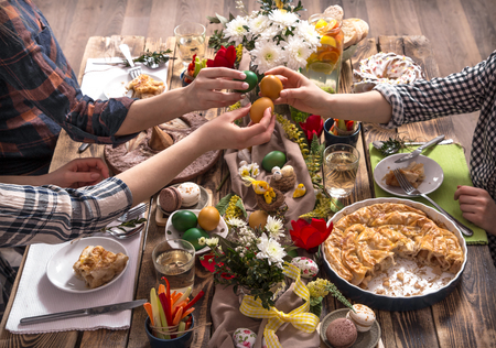 Home Holiday friends or family at the festive Easter table with Easter colored eggs. The concept of the celebrationの写真素材