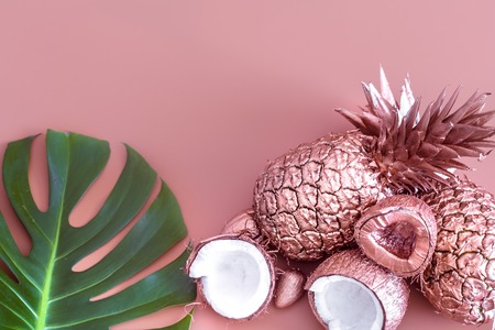 Fashionable colored summer layout of fruits painted in gold color and tropical leaf, Pineapple and coconut on a colored background , creative advertising design.Top viewの写真素材