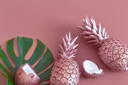 Fashionable colored summer layout of fruits painted in gold color and tropical leaf, Pineapple and coconut on a colored background , creative advertising design.Top viewの写真素材