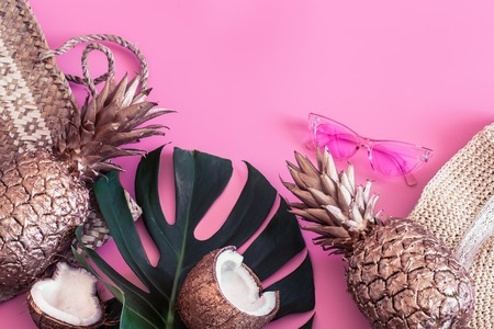Summer tropical background with painted gold pineapple and summer accessories, on a colored pink background, the concept of creativity and styleの写真素材