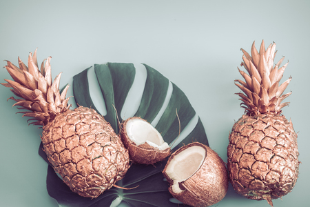 Summer tropical background with Golden pineapples and coconuts with tropical leaf on blue pastel background, summer creativity and style conceptの写真素材