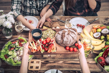 Enjoying dinner with my friends. Top view of a group of people dining together, sitting at a rustic wooden table, the concept of celebration and healthy home-cooked foodの写真素材