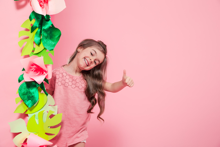 Little cute girl on color background with paper flowers , place for text, summer advertising conceptの写真素材