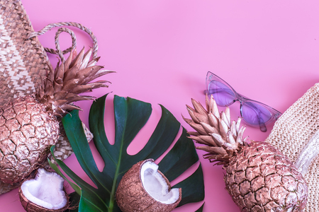 Summer tropical background with painted gold pineapple and summer accessories, on a colored pink background, the concept of creativity and styleの写真素材