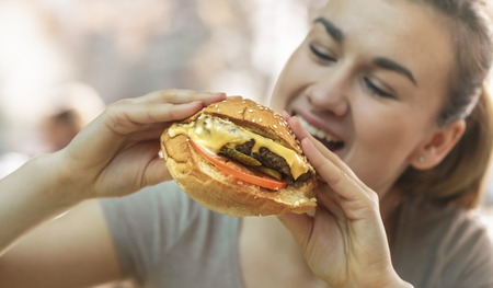 Young woman in cafe eating tasty sandwich, fast food conceptの写真素材
