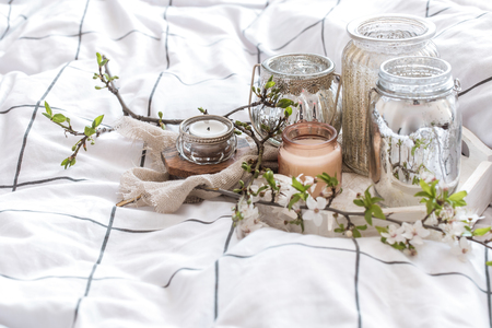 Home interior. Cozy still life with different candles in bed and spring flowersの写真素材