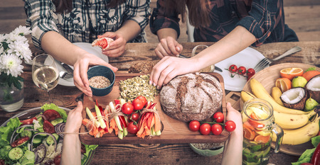 Enjoying dinner with my friends. Top view of a group of people dining together, sitting at a rustic wooden table, the concept of celebration and healthy home-cooked foodの写真素材