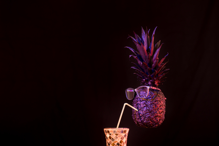 the club concept ,black and gold pineapple with sunglasses, drinking a cocktail with straws on a black isolated background, Studio shot, creativity and artの写真素材
