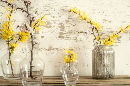 Home cozy beautiful decor, different vases and candles with spring flowers , on a wooden background , the concept of interior detailsの写真素材