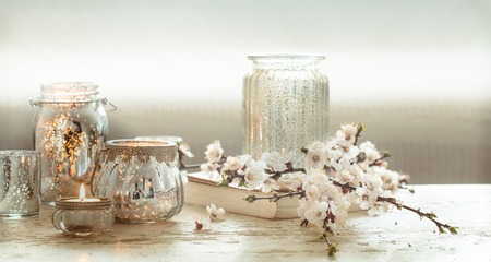 Still-life. Home cozy beautiful decor in the living room , a vase with spring flowers and candles on a wooden background , the concept of interior detailsの写真素材