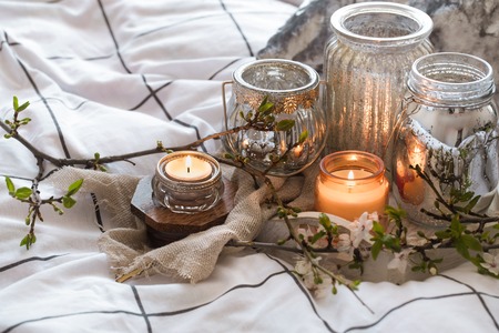 Home interior. Cozy still life with different candles in bed and spring flowersの写真素材