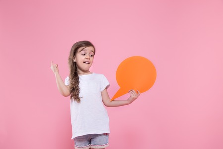 Cute little girl with speech icon on pink background .The concept of communication and communication . Studio shootingの写真素材