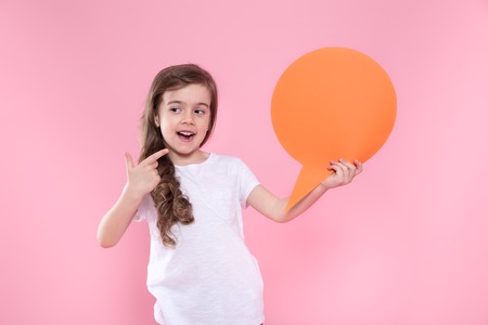 Cute little girl with speech icon on pink background .The concept of communication and communication . Studio shootingの写真素材