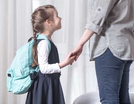 Parent and elementary school student go hand in hand on a light background . Back to school conceptの写真素材