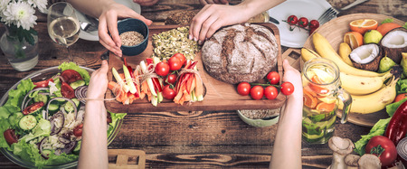 Enjoying dinner with my friends. Top view of a group of people dining together, sitting at a rustic wooden table, the concept of celebration and healthy home-cooked foodの写真素材