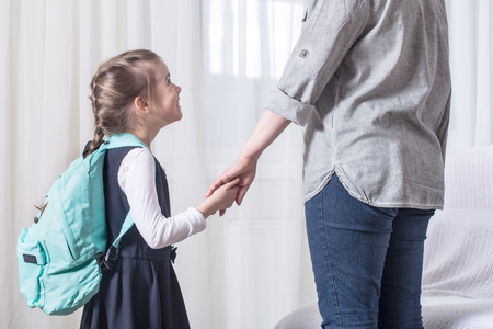 Parent and elementary school student go hand in hand on a light background . Back to school conceptの写真素材