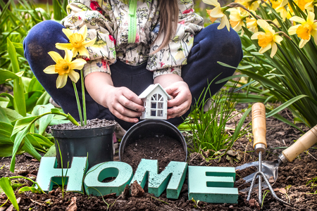 Earth Day .A child in the background of the garden holding a small wooden house. Wooden letters with the inscription homeの写真素材