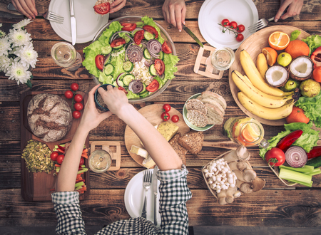 Enjoying dinner with my friends. Top view of a group of people dining together, sitting at a rustic wooden table, the concept of celebration and healthy home-cooked foodの写真素材
