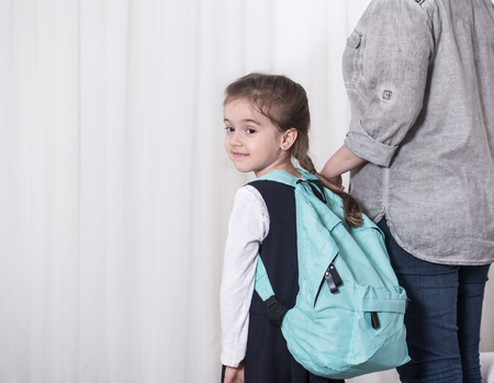 Parent and elementary school student go hand in hand on a light background . Back to school conceptの写真素材